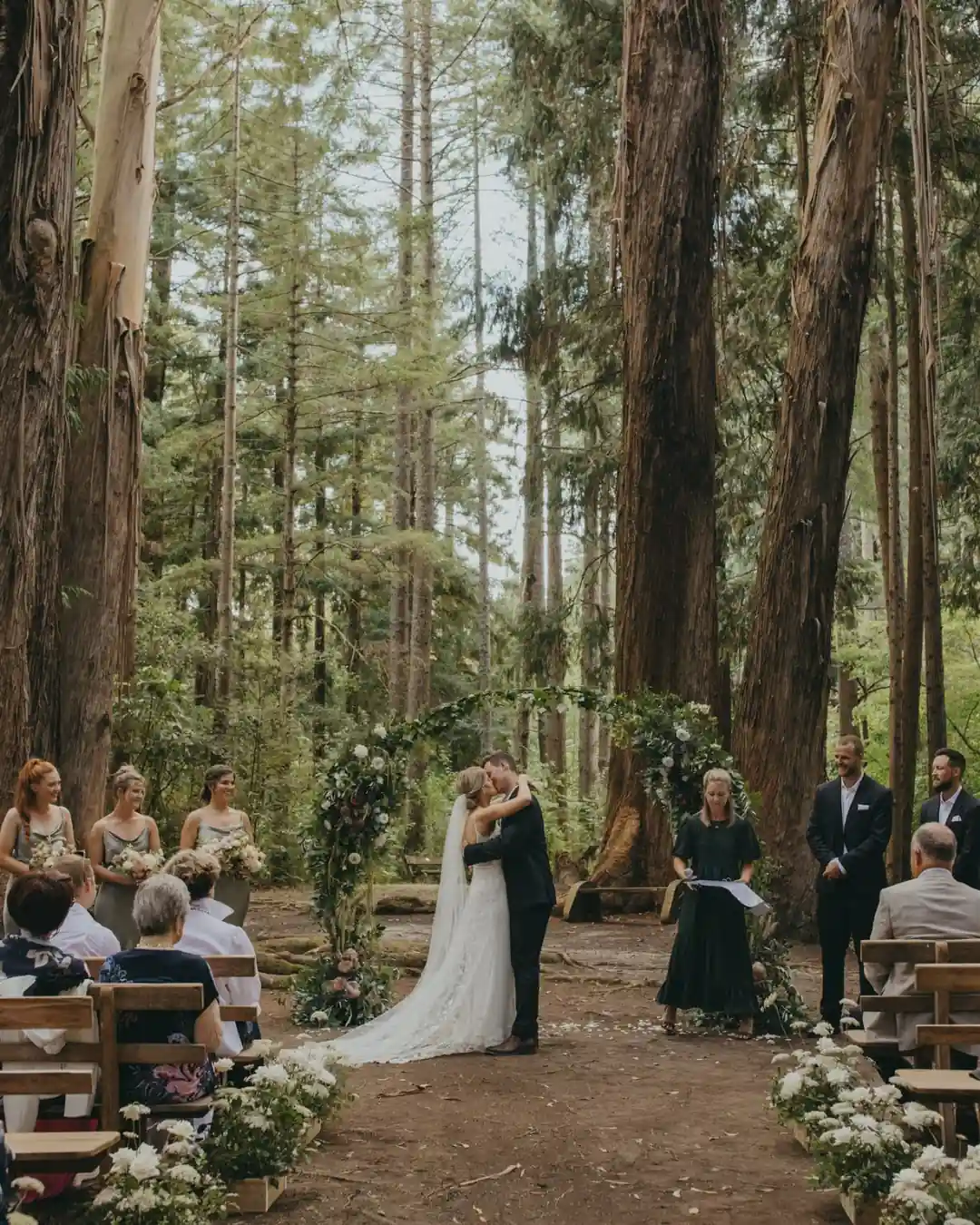 Forest wedding ceremony under towering trees at Eastwoodhill Arboretum near Gisborne