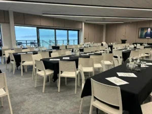 Conference setup with round tables and TV screen at Midway Hub Gisborne overlooking ocean