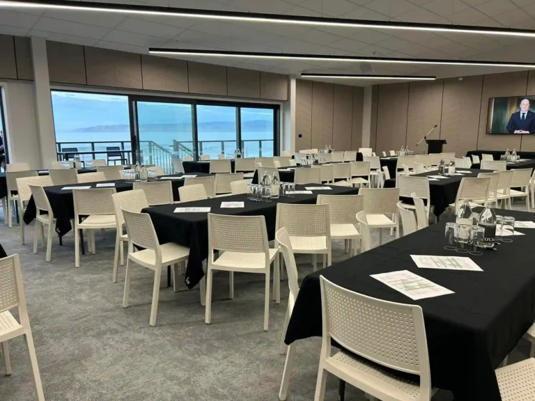 Conference setup with round tables and TV screen at Midway Hub Gisborne overlooking ocean