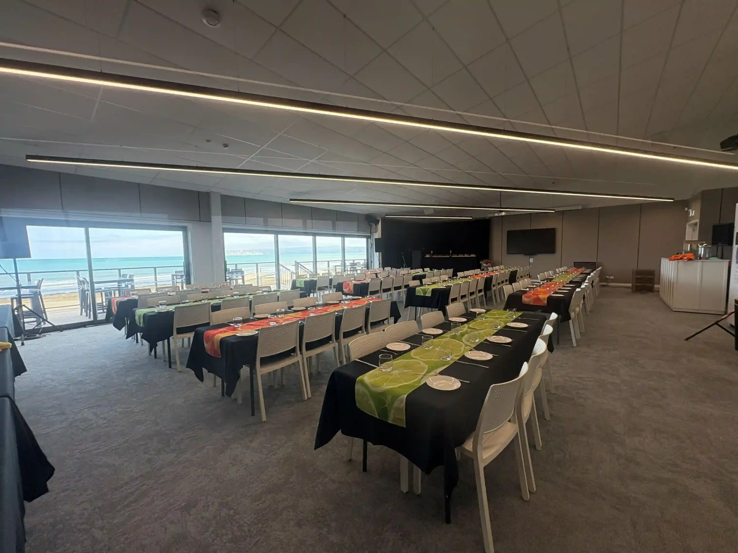 Banquet table setup with citrus runners and ocean views in Mana Moana Lounge, Midway Hub Gisborne