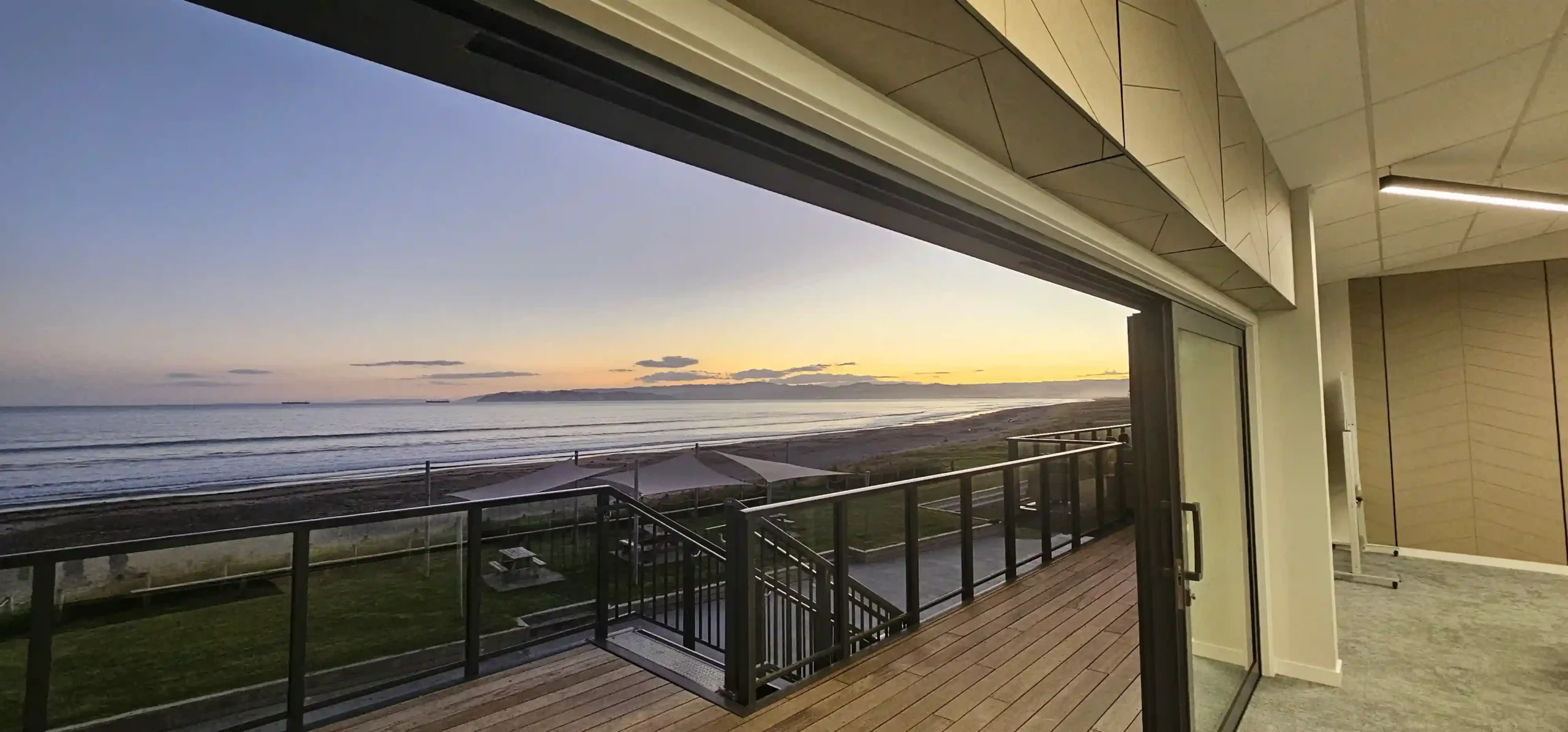 Midway Hub function room with bifold doors open to deck and ocean sunset view, Gisborne venue hire NZ