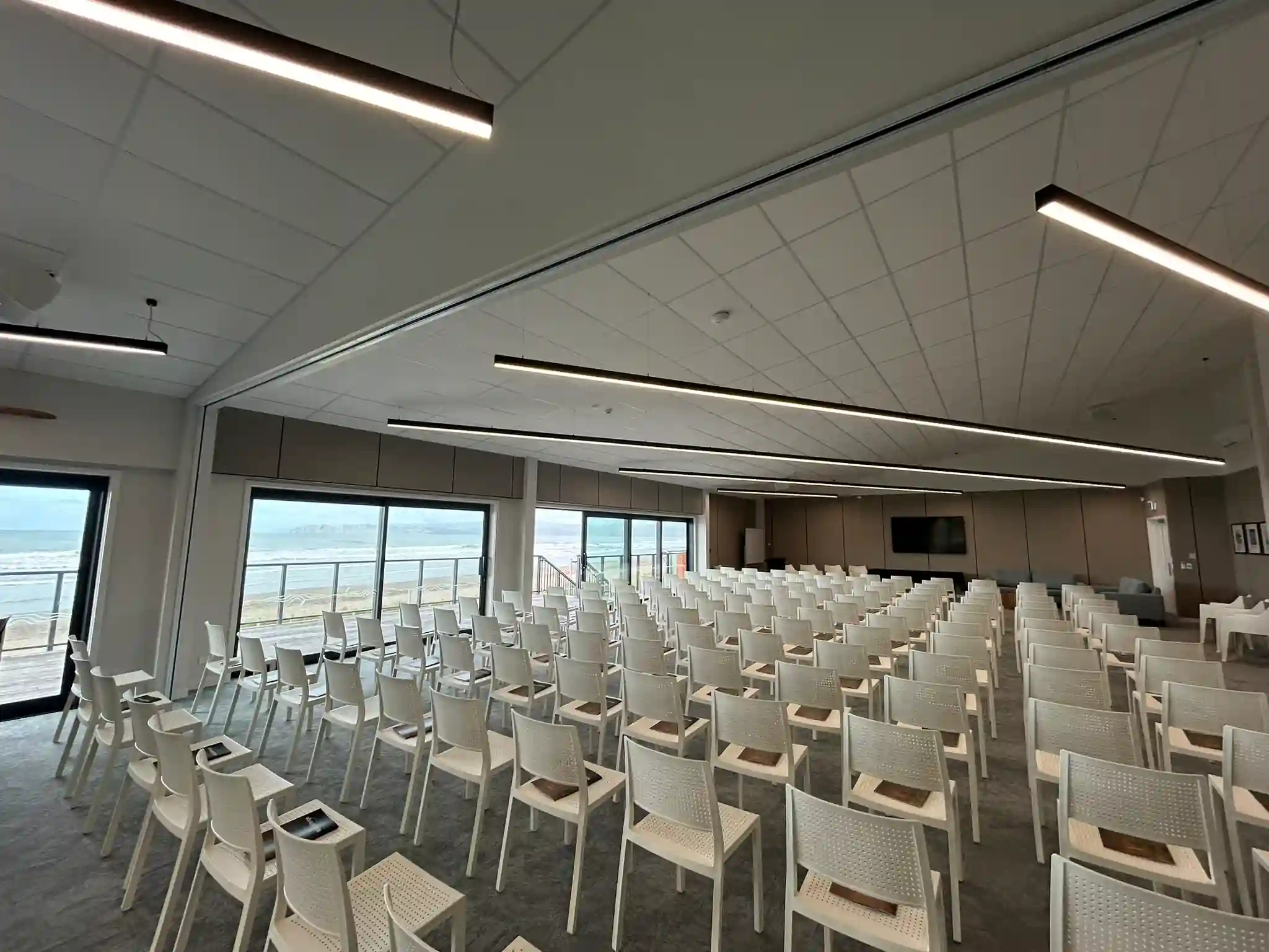 Theatre-style seating layout with ocean views through floor-to-ceiling windows in Mana Moana Lounge, Gisborne