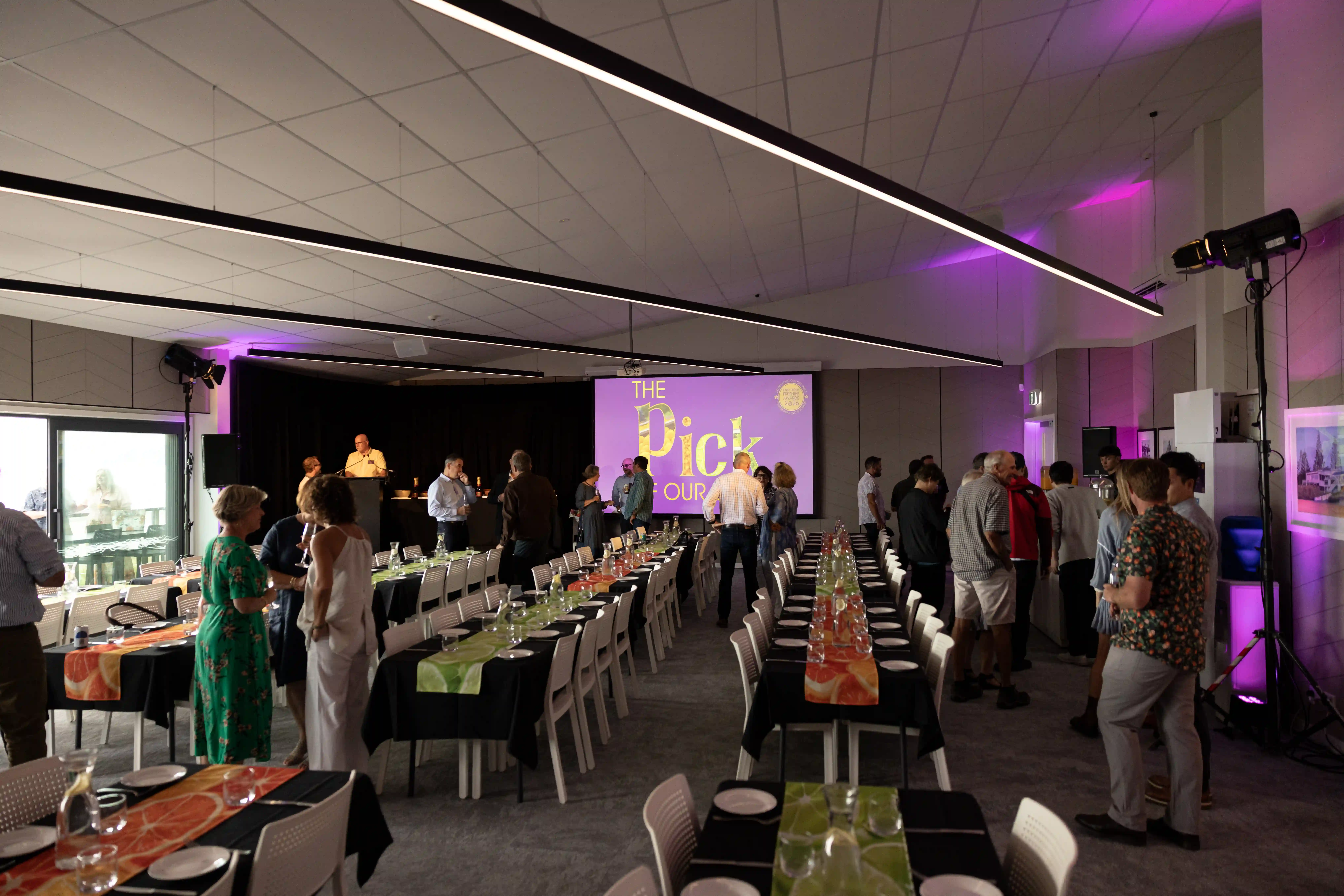 Corporate event guests mingling with purple uplighting at Midway Community Hub Gisborne