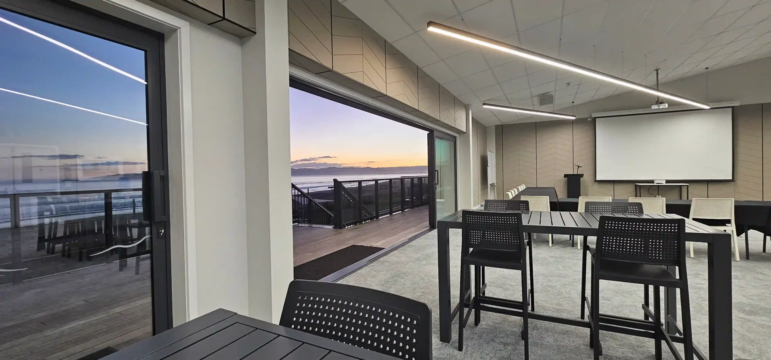 Event setup with high tables and projector screen at sunset in Midway Hub function room Gisborne