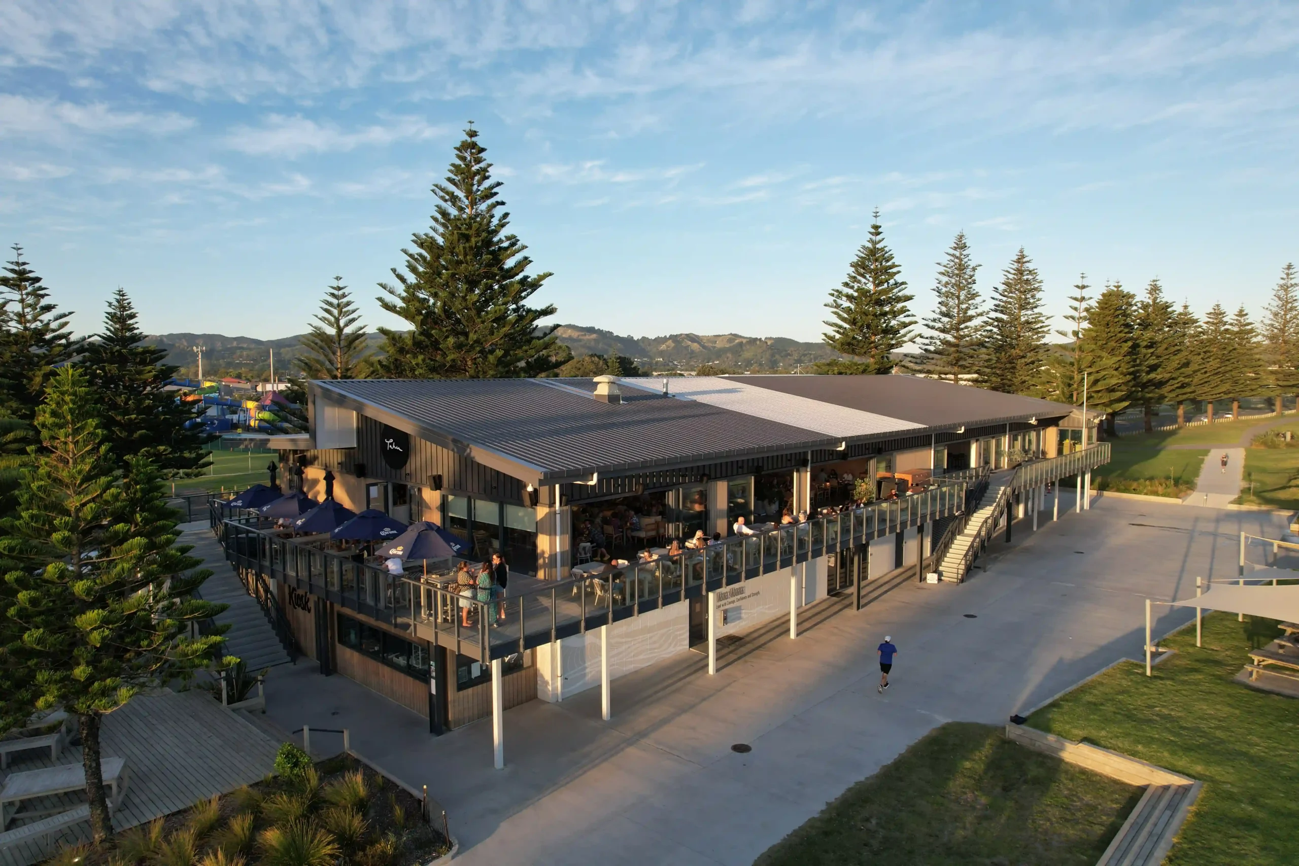 Aerial view of guests dining on an outdoor deck with umbrellas at a summer work Christmas party