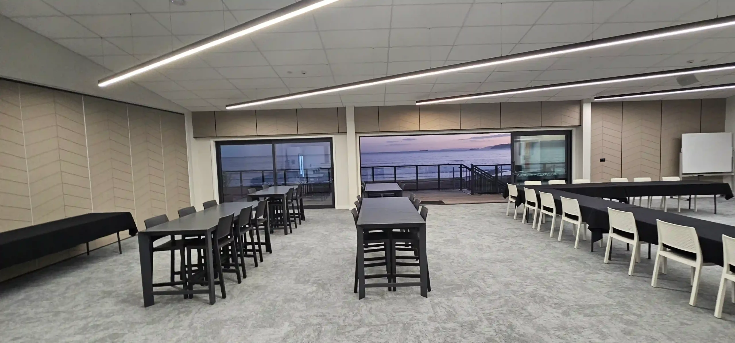 Cocktail-style work Christmas function at sunset with high tables and ocean views