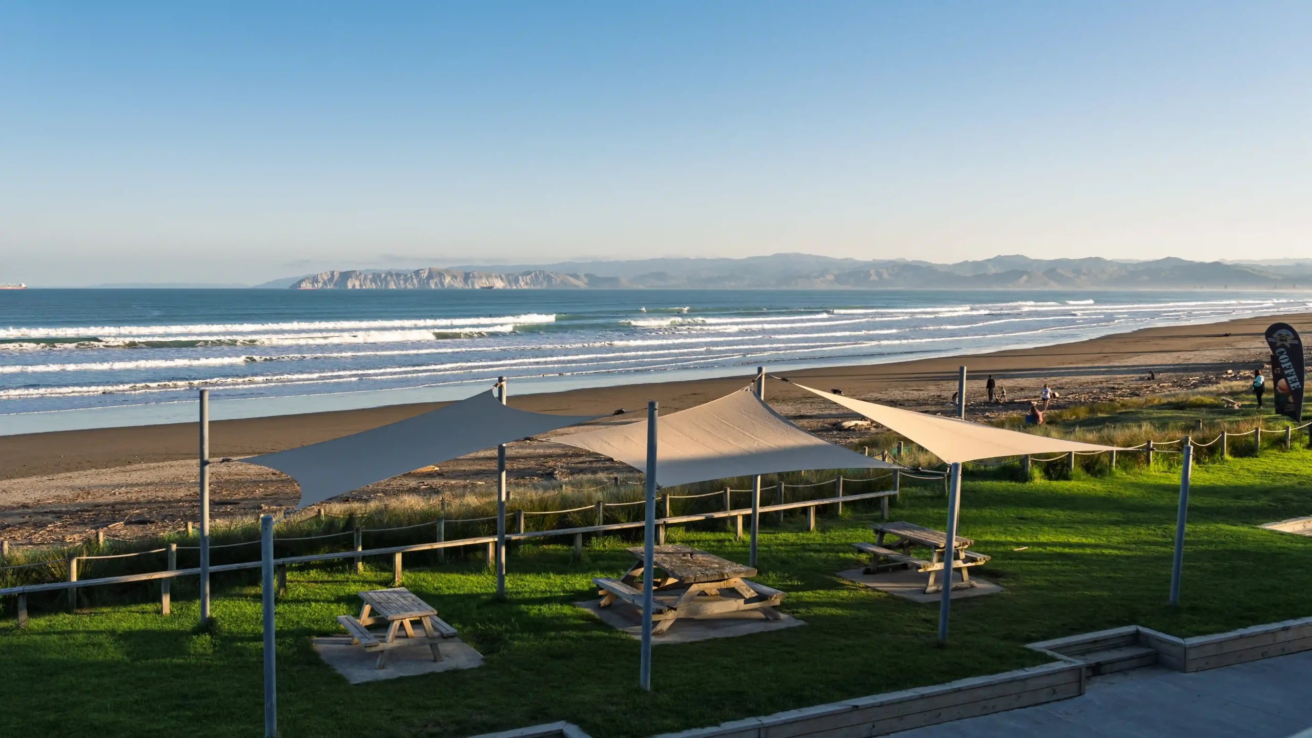Outdoor picnic area with shade sails and ocean views for a summer work Christmas party in NZ